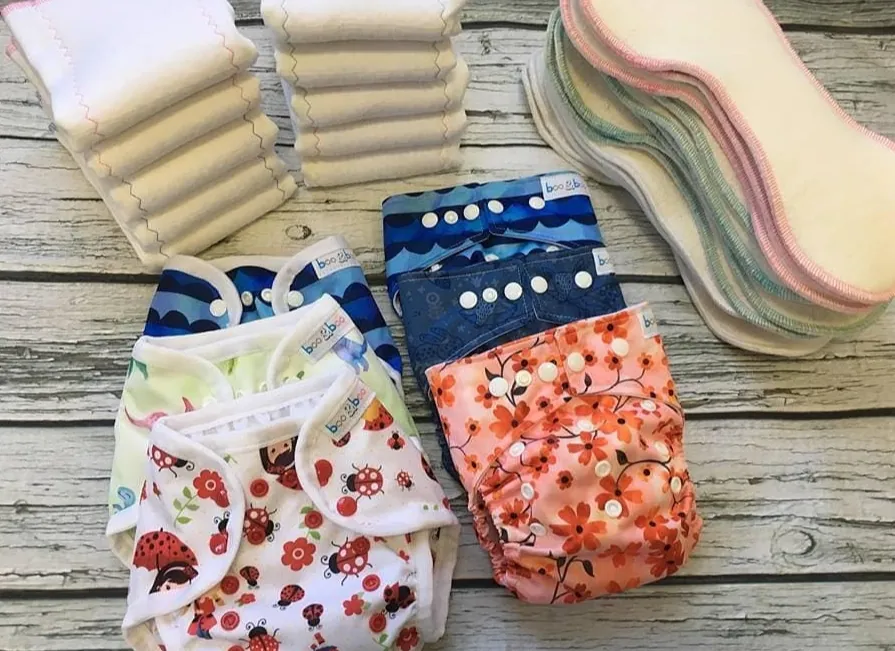 Stacks of handmade cloth diapers and absorbent inserts laid out on weathered wood